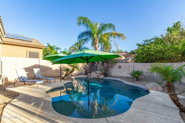 a backyard of a house with table and chairs under an umbrella