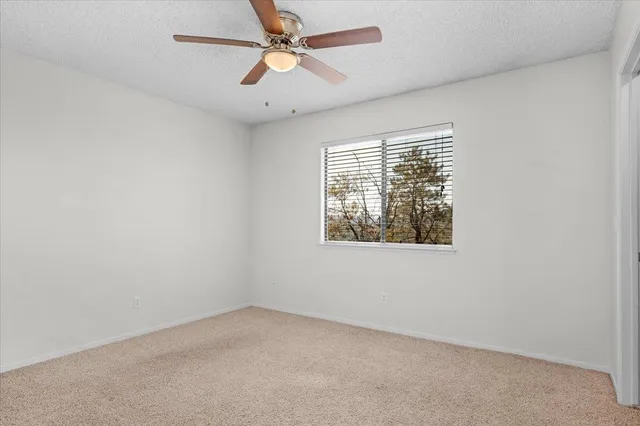 an empty room with a window and a fan