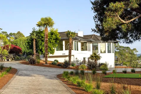 a front view of a house with a yard and potted plants