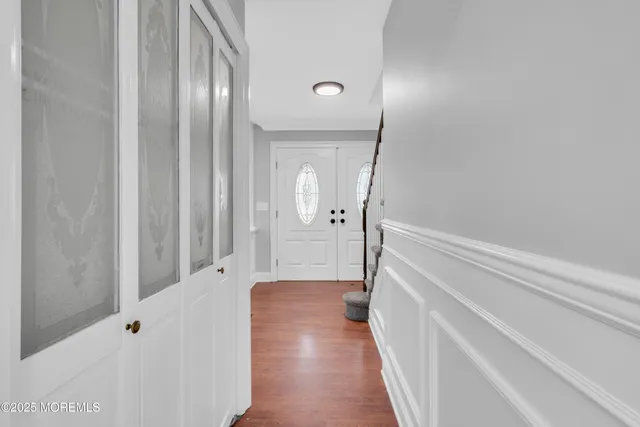 a view of a hallway with wooden floor and a bathroom