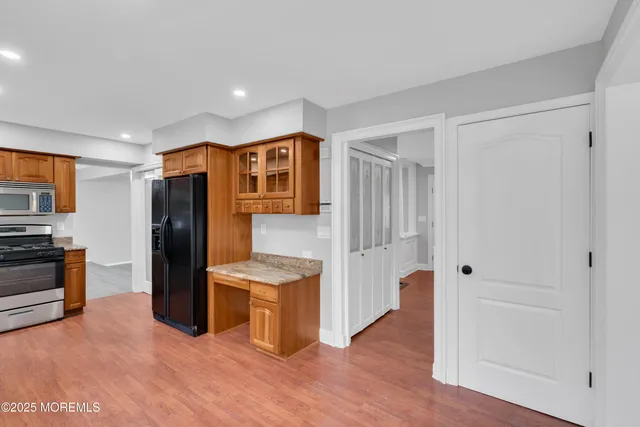 a view of kitchen with stainless steel appliances wooden floor and chair