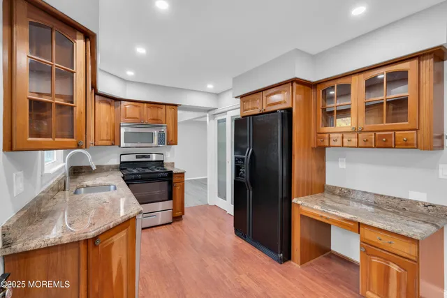 a kitchen with stainless steel appliances granite countertop wooden cabinets a refrigerator and a sink