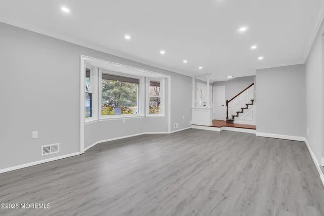 an empty room with wooden floor cabinet and windows