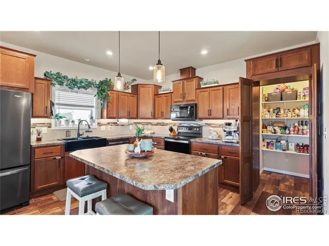 a kitchen with stainless steel appliances kitchen island granite countertop a table chairs and a refrigerator