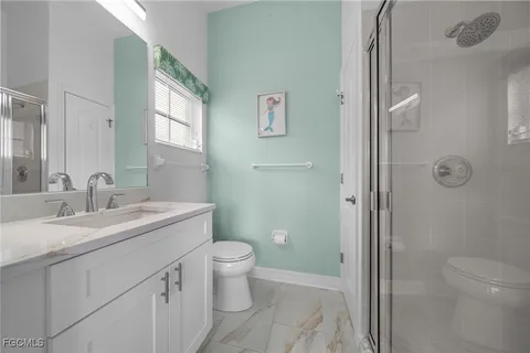 a bathroom with a granite countertop sink a toilet and shower