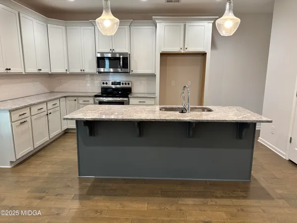 a kitchen with stainless steel appliances granite countertop a stove a sink and a microwave