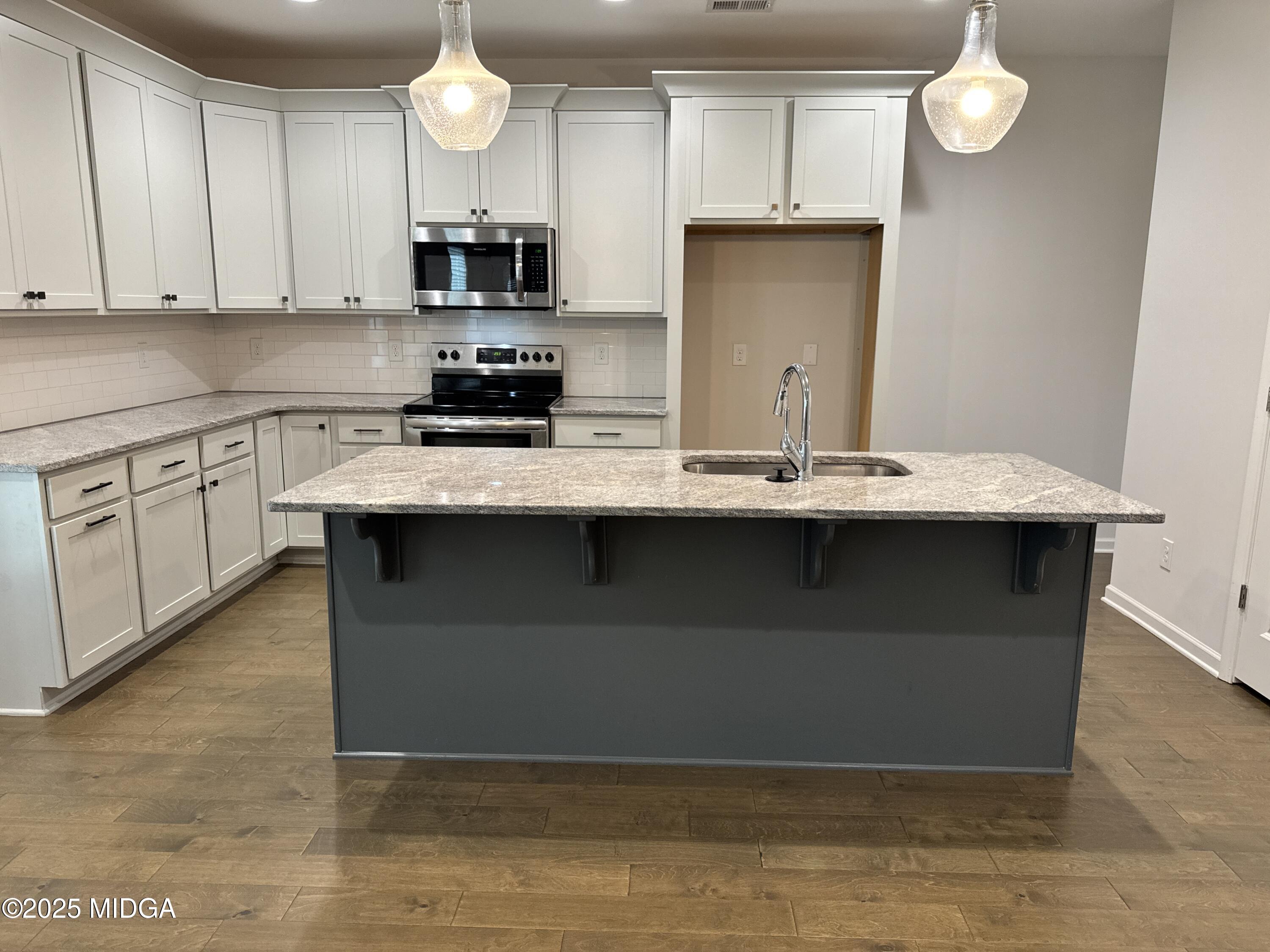 1082 Victorian Boulevard Forsyth, GA 31029 - Photo 5 of 23 a kitchen with stainless steel appliances granite countertop a stove a sink and a microwave