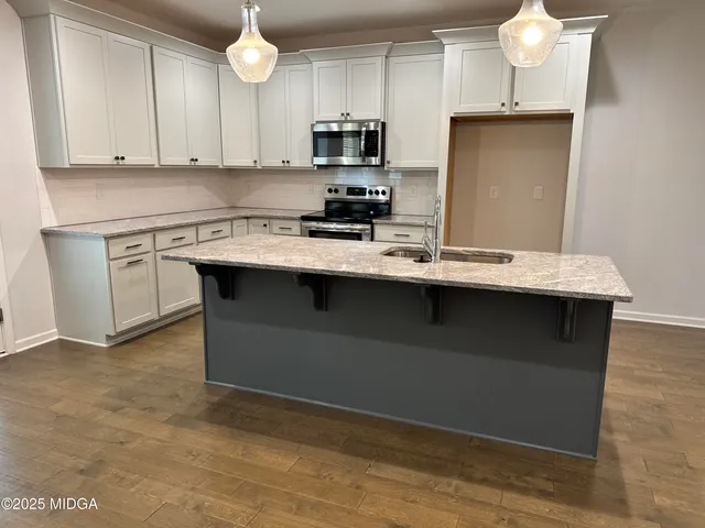 a kitchen with stainless steel appliances granite countertop a sink a stove and a microwave