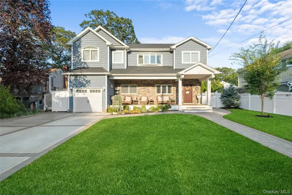 a view of a white house with a big yard and large tree