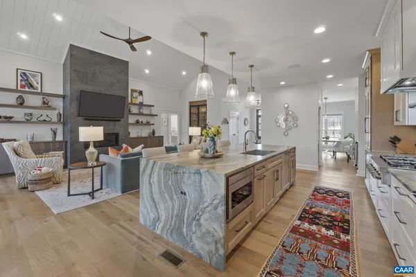 a large white kitchen with a large island oven a sink and stainless steel appliances