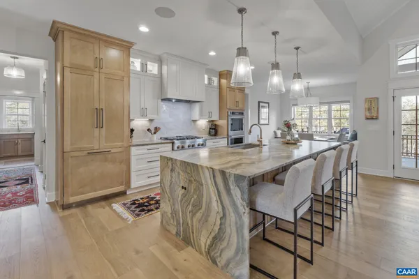 a kitchen with stainless steel appliances kitchen island granite countertop a table chairs and a refrigerator