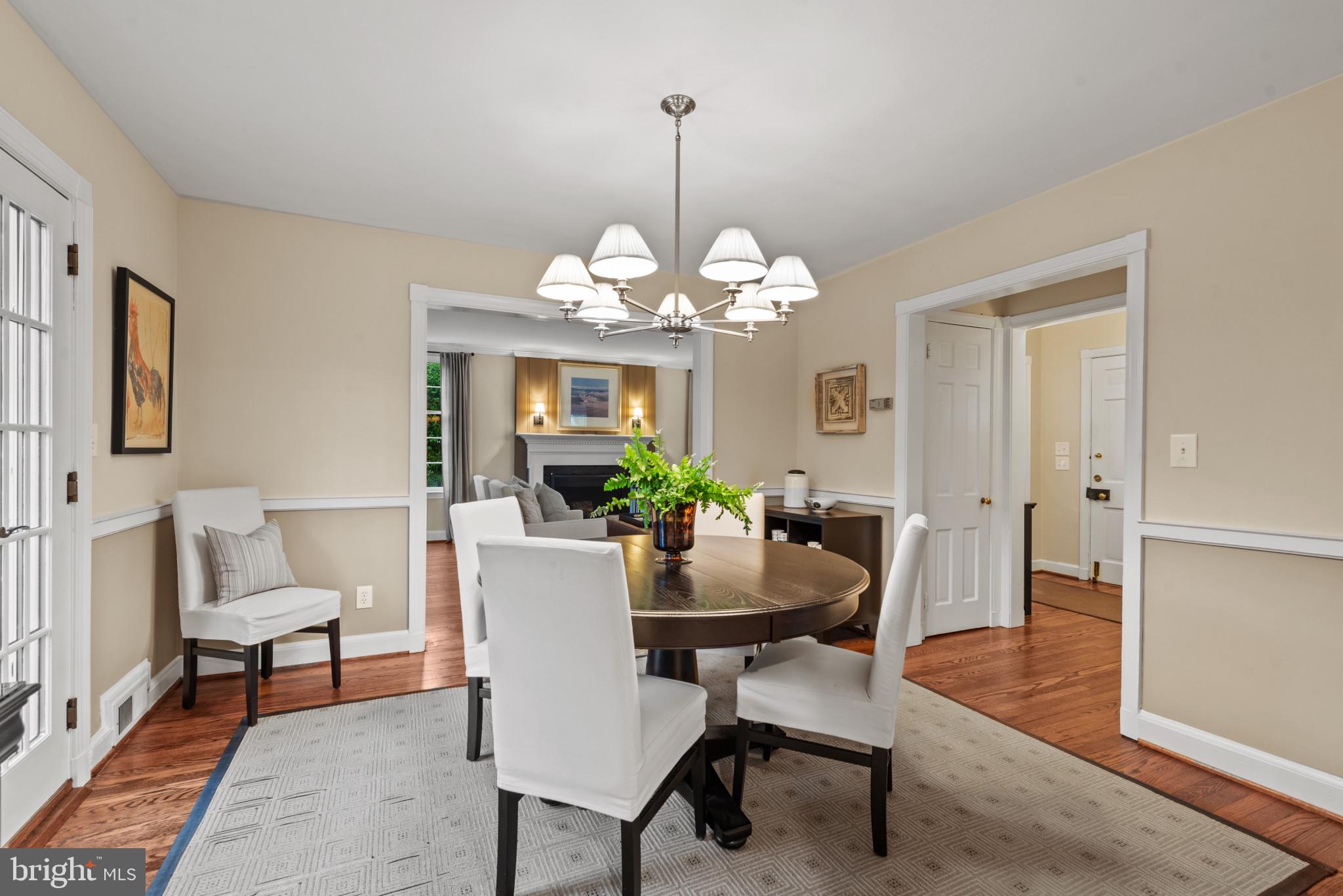 2443 Pickwick Road Baltimore, MD 21207 - Photo 16 of 108 a dining room with wooden floor a chandelier a wooden table and chairs