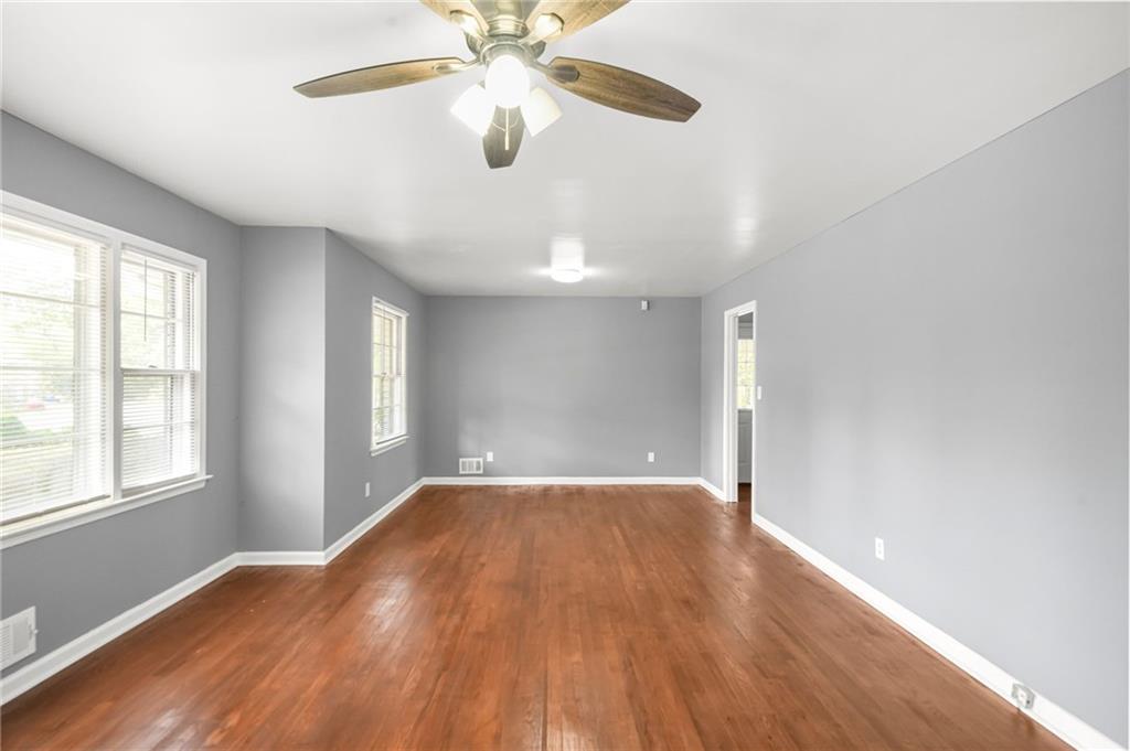 1393 Idlewood Road Tucker, GA 30084 - Photo 10 of 32 an empty room with wooden floor chandelier fan and windows