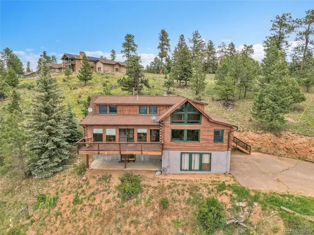 a front view of a house with a yard and mountain view in back