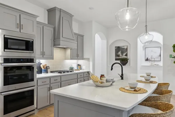 a kitchen with stainless steel appliances granite countertop a stove a sink dishwasher and microwave with wooden floor