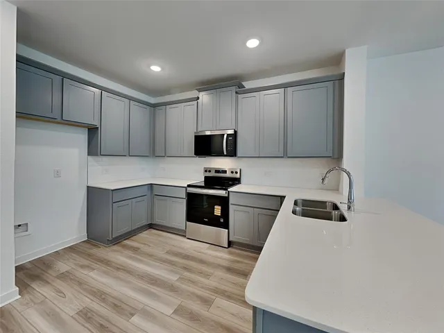 a kitchen with granite countertop a refrigerator stove top oven and sink