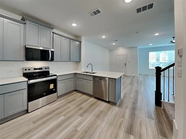 a kitchen with stainless steel appliances kitchen island granite countertop a stove a sink and a refrigerator
