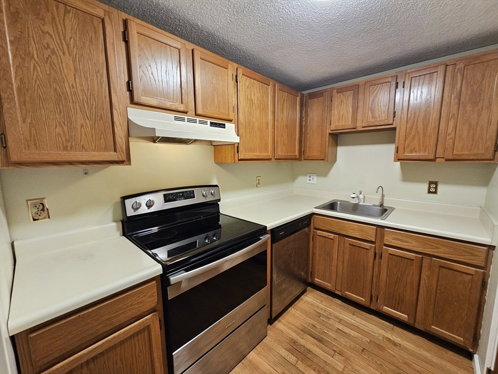 35 Prospect Street, Unit 215 Woburn, MA 01801 - Photo 8 of 37 a kitchen with wooden cabinets and a stove top oven