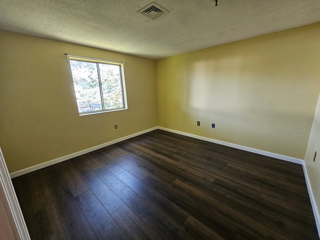 35 Prospect Street, Unit 215 Woburn, MA 01801 - Photo 9 of 37 an empty room with wooden floor and windows