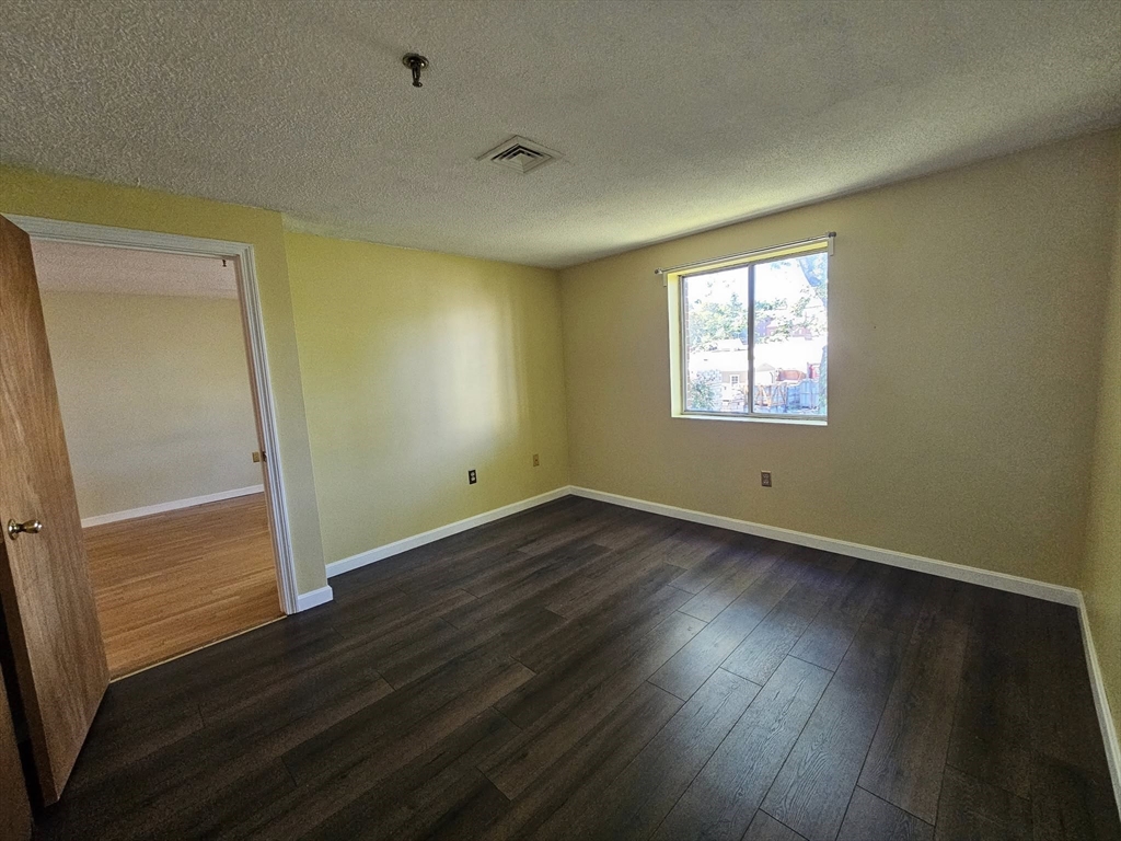 35 Prospect Street, Unit 215 Woburn, MA 01801 - Photo 10 of 37 an empty room with wooden floor and windows