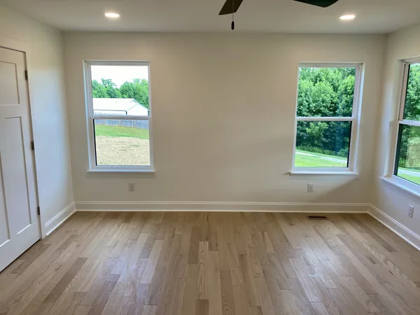 an empty room with wooden floor and windows