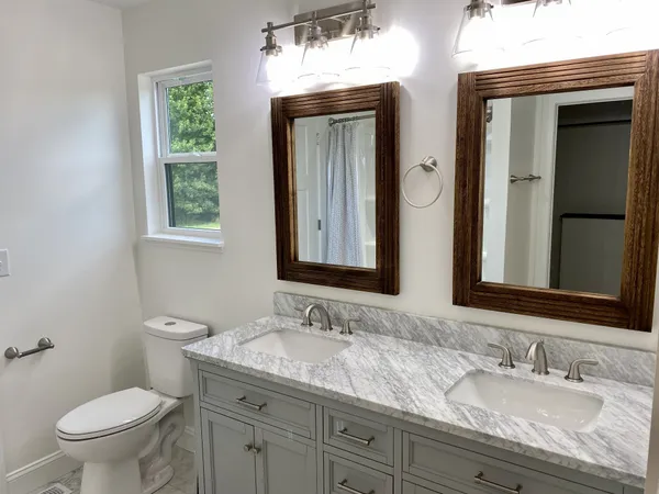 a bathroom with a granite countertop sink a toilet and a mirror