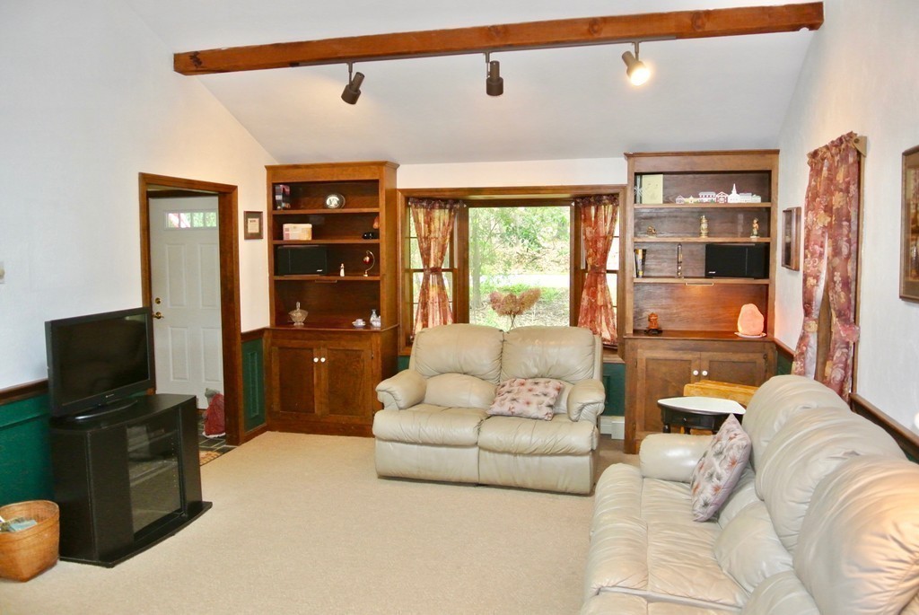 202 Pepperell Road Groton, MA 01450 - Photo 11 of 30 a living room with furniture a flat screen tv and a floor to ceiling window
