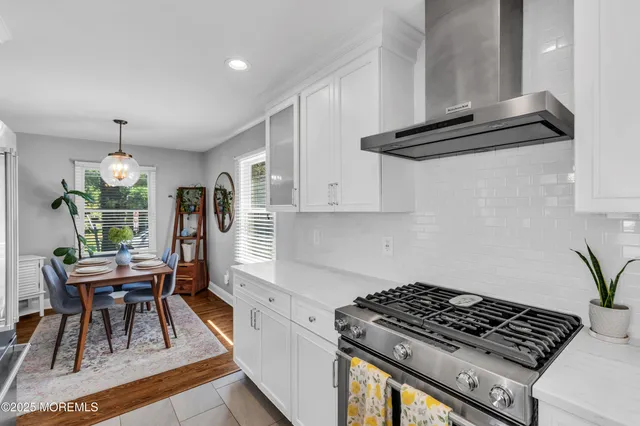 a kitchen with stainless steel appliances granite countertop a stove a refrigerator a sink dishwasher a dining table and chairs with wooden floor