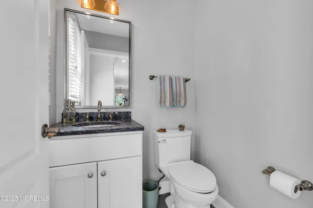 a bathroom with a granite countertop toilet sink and mirror
