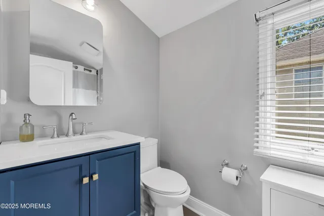 a bathroom with a toilet a sink a mirror and a window