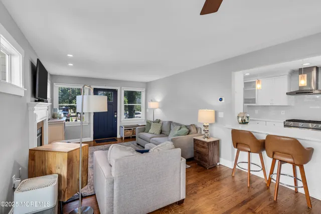 a living room with furniture a flat screen tv and a refrigerator