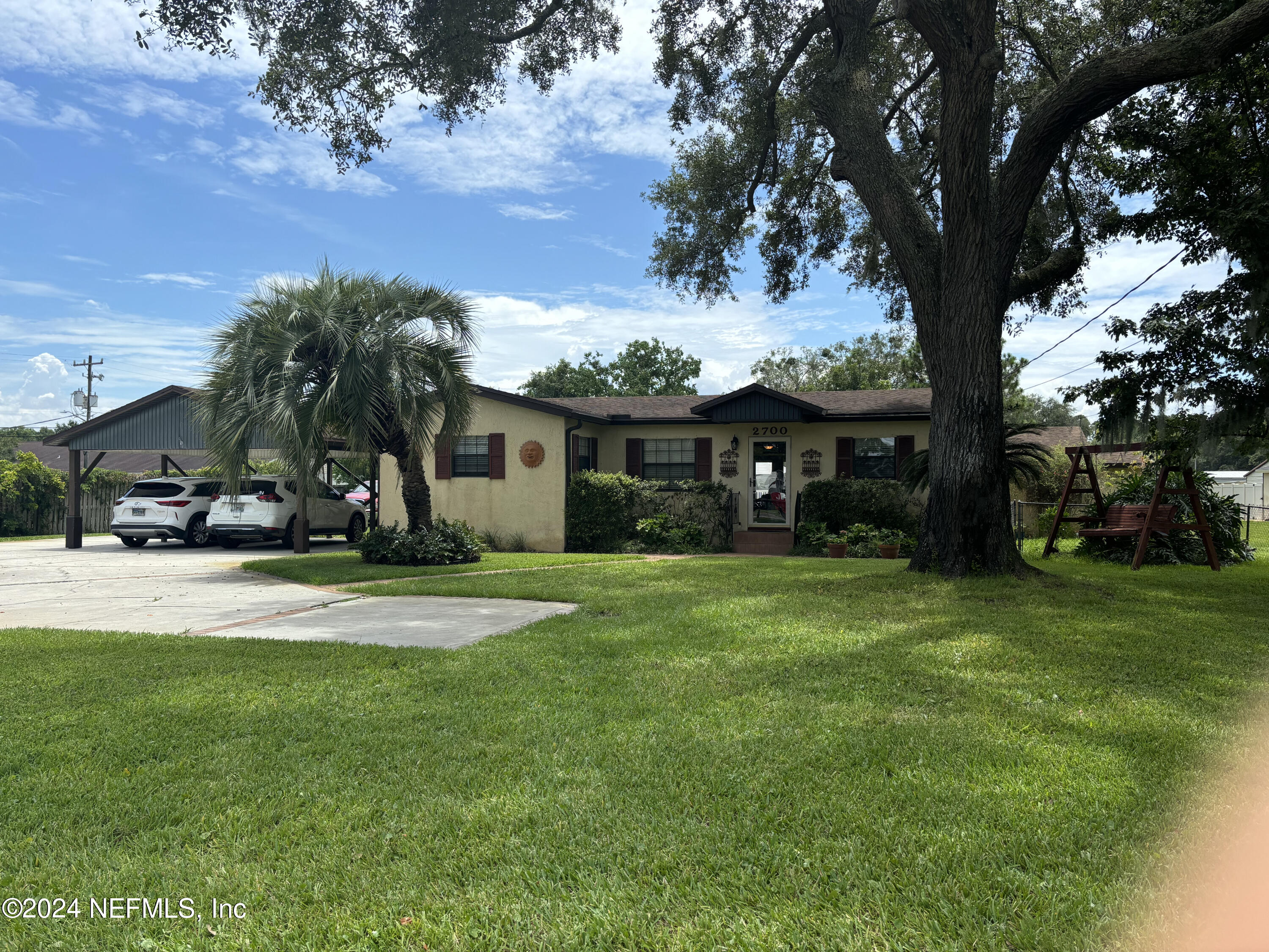a front view of a house with a garden and trees