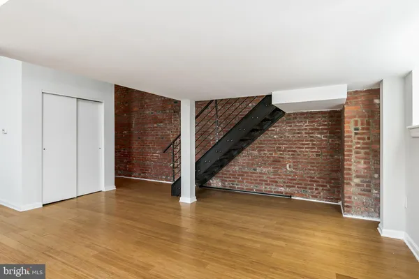a view of an empty room with wooden floor and stairs
