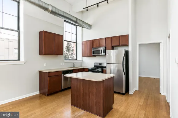 a kitchen with stainless steel appliances granite countertop a refrigerator a sink a stove a microwave and wooden floors