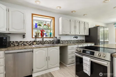 a kitchen with stainless steel appliances granite countertop a stove a sink and a refrigerator