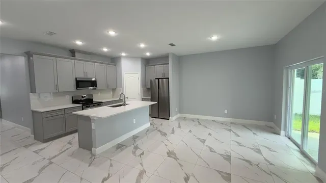 a large kitchen with granite countertop a sink and white cabinets