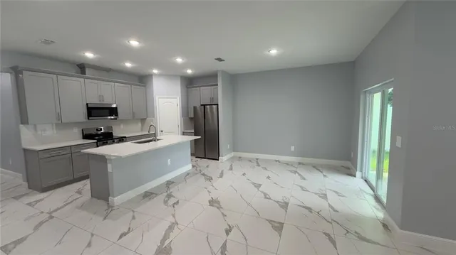 a kitchen with granite countertop a refrigerator and a stove top oven