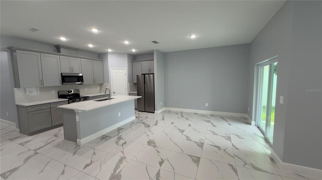 706 South Thacker Avenue Kissimmee, FL 34741 - Photo 16 of 36 a kitchen with granite countertop a refrigerator and a stove top oven