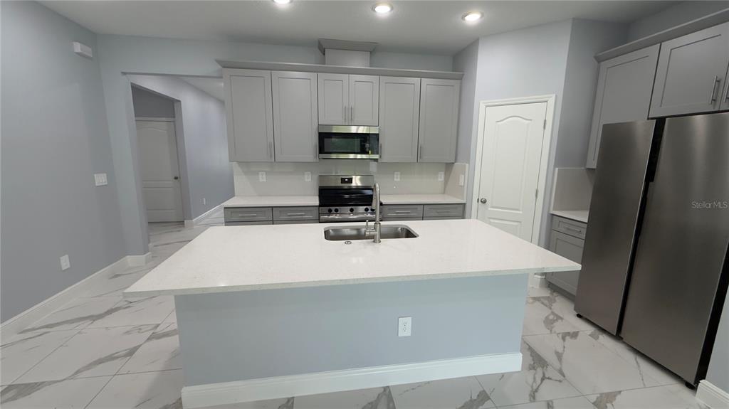 706 South Thacker Avenue Kissimmee, FL 34741 - Photo 17 of 36 a kitchen with kitchen island a sink a stove a refrigerator and cabinets