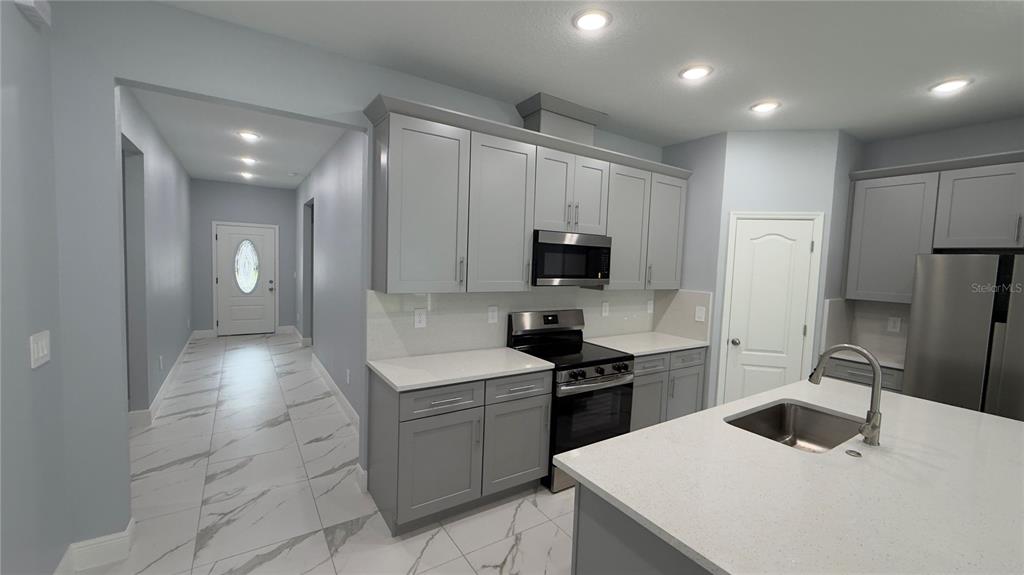 706 South Thacker Avenue Kissimmee, FL 34741 - Photo 18 of 36 a kitchen with a sink stainless steel appliances and white cabinets
