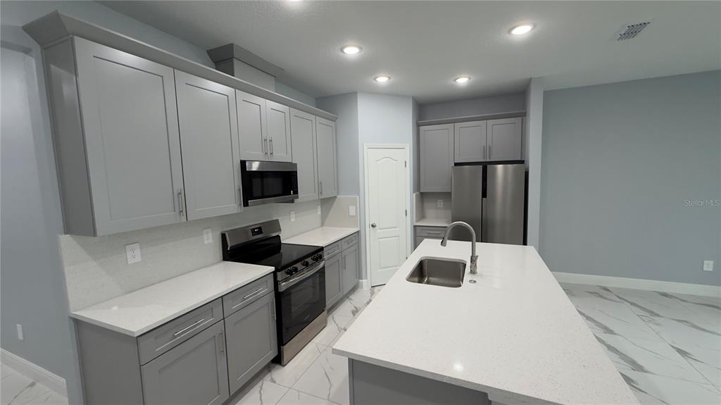 706 South Thacker Avenue Kissimmee, FL 34741 - Photo 22 of 36 a kitchen with stainless steel appliances a stove microwave and refrigerator