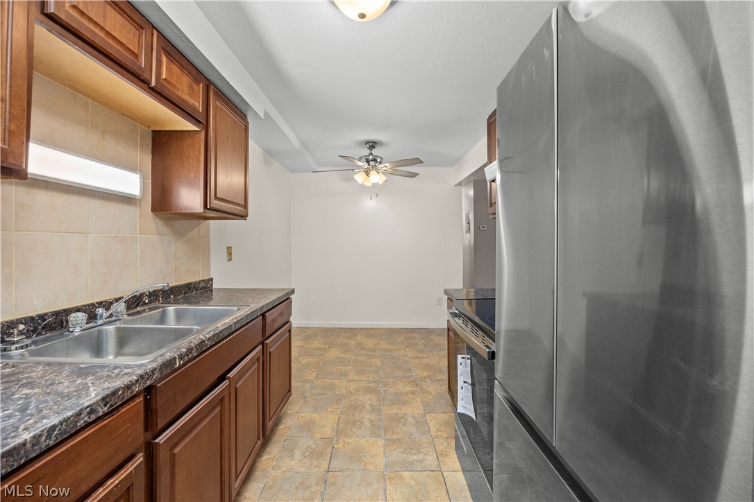 5382 Lee Road, Unit 102 Maple Heights, OH 44137 - Photo 16 of 25 Kitchen with stainless steel appliances, a ceiling fan, stone finish floors, and wood finish cabinets