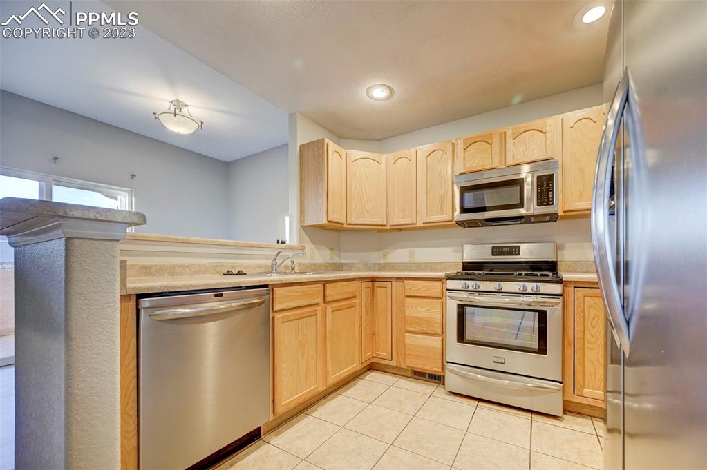 5433 Prominence Point Colorado Springs, CO 80923 - Photo 12 of 26 a kitchen with stainless steel appliances granite countertop a stove top oven a sink dishwasher a refrigerator and a microwave