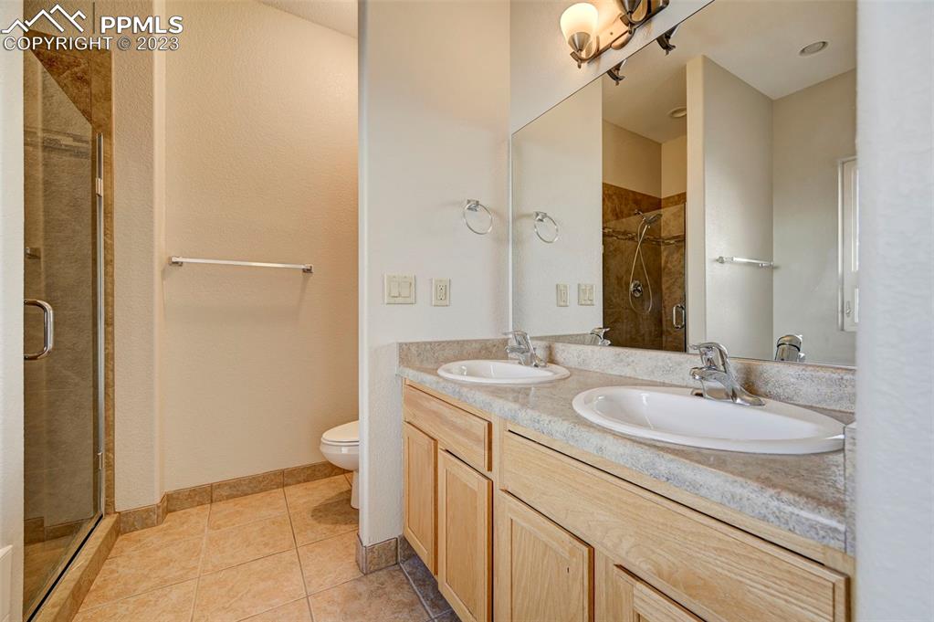 5433 Prominence Point Colorado Springs, CO 80923 - Photo 24 of 26 a bathroom with a granite countertop sink a toilet and a mirror