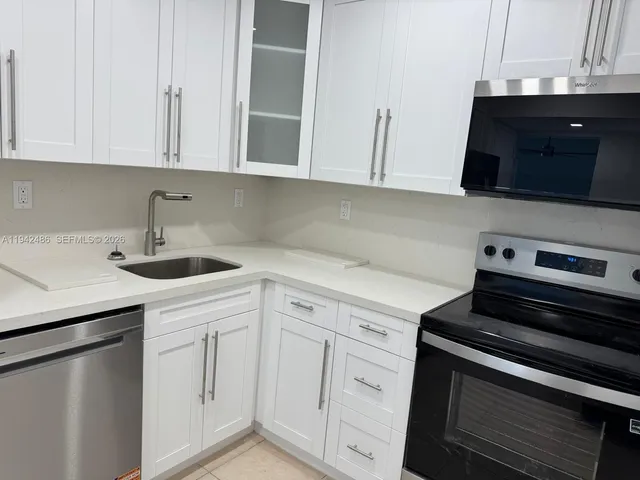 a kitchen with white cabinets and black appliances