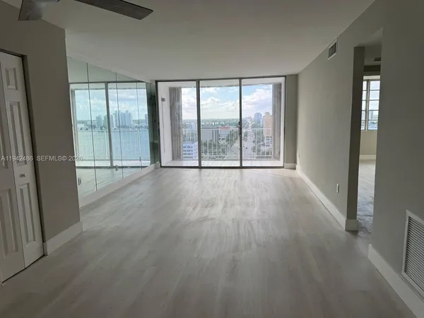 an empty room with wooden floor and glass door