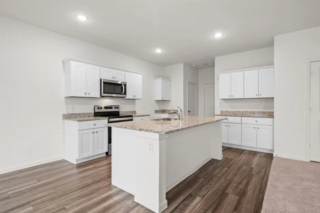 a kitchen with granite countertop a sink stove and cabinets