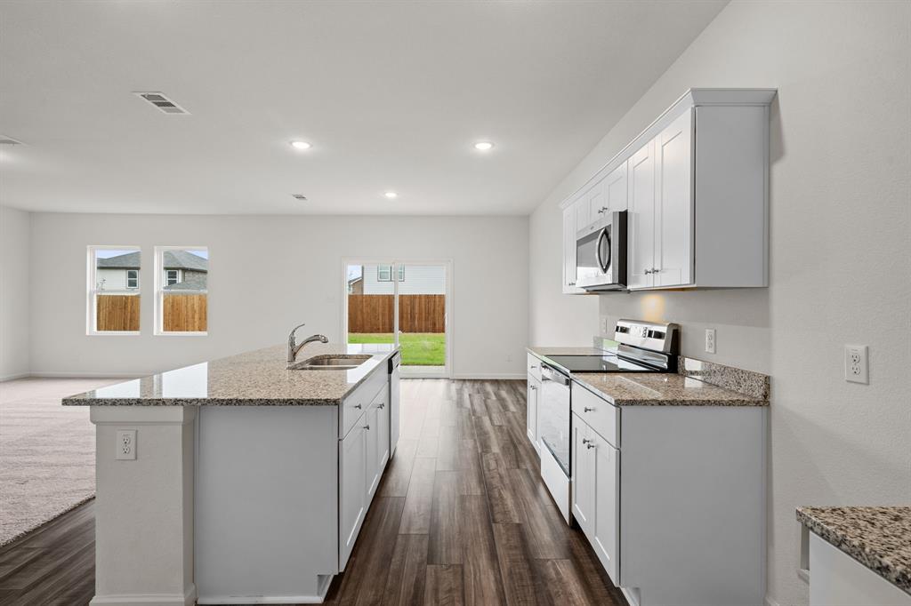 619 Colgate Circle Princeton, TX 75407 - Photo 17 of 31 a kitchen with granite countertop a sink stove and cabinets