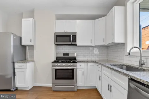 a kitchen with cabinets stainless steel appliances a sink and wooden floor