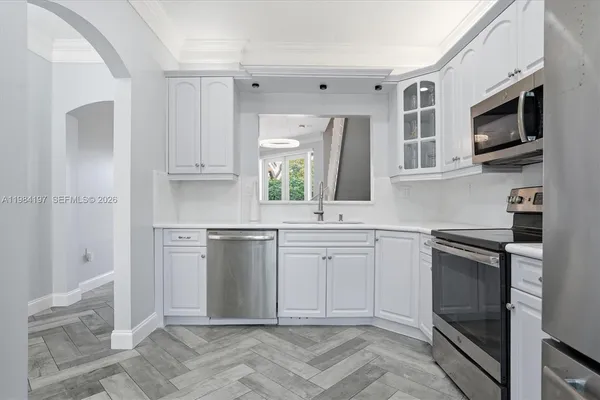 a kitchen with white cabinets stainless steel appliances and a window